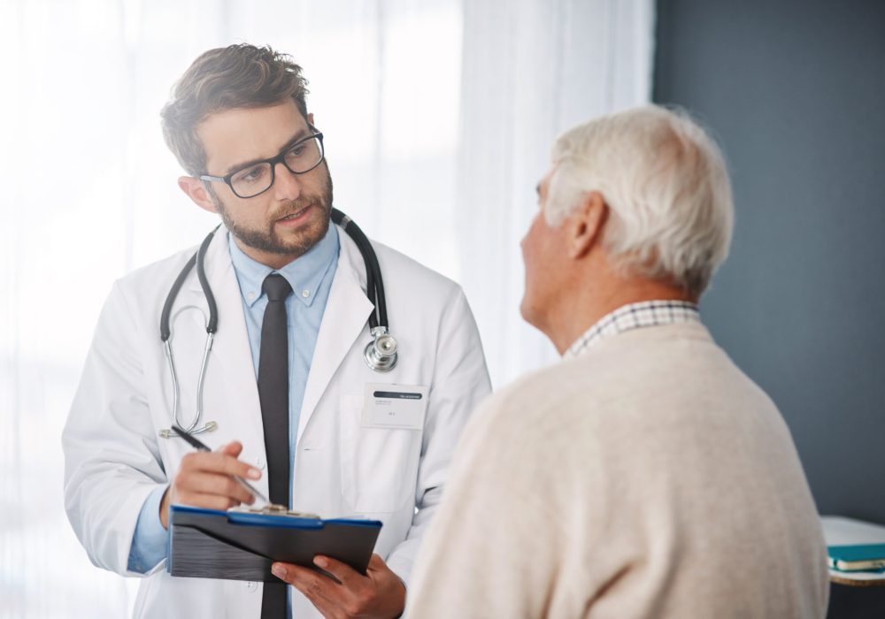 Cropped shot of a young male doctor going through medical records with his senior male patient.